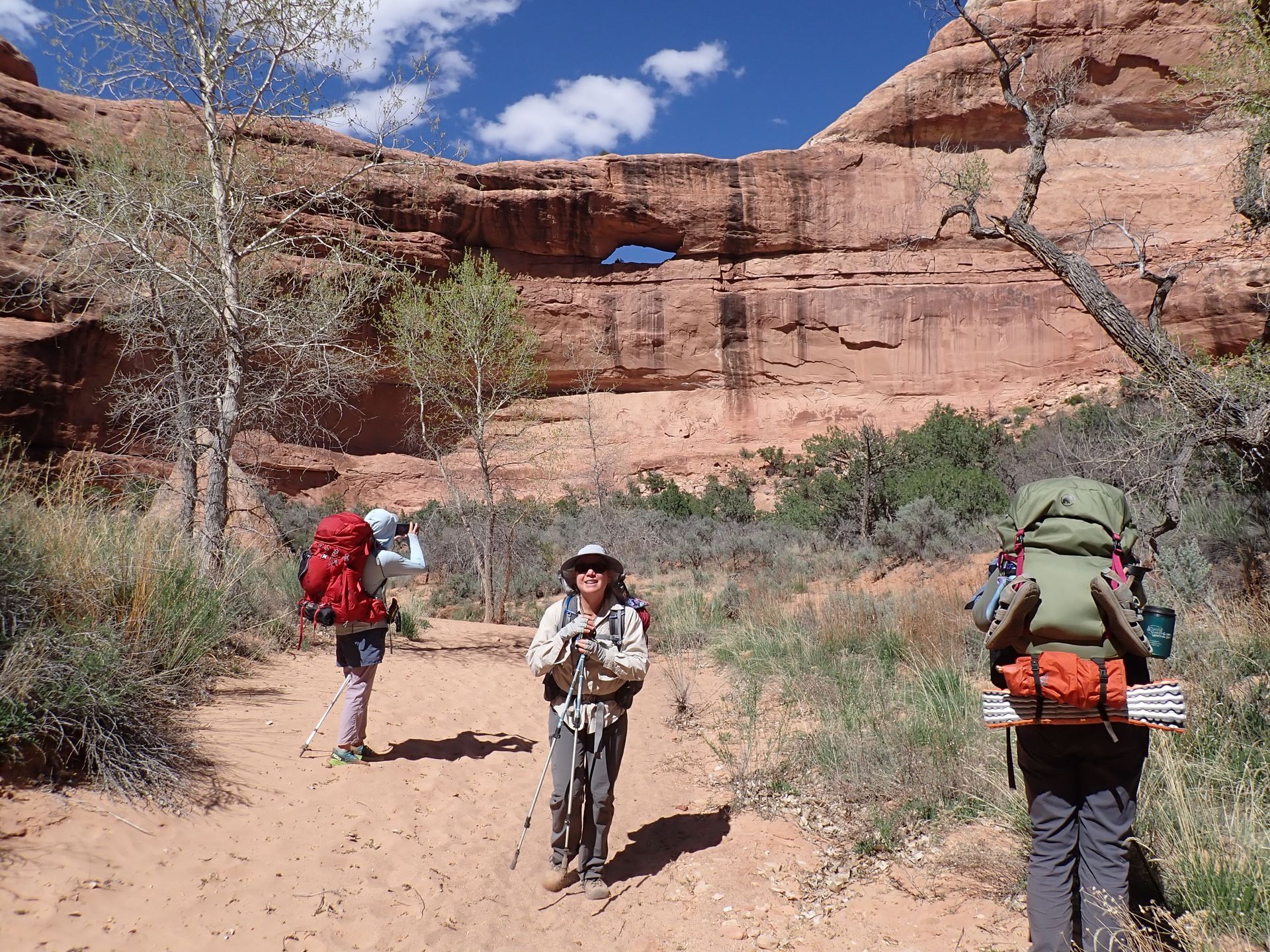 A group of people with backpacks are walking down a dirt path.
