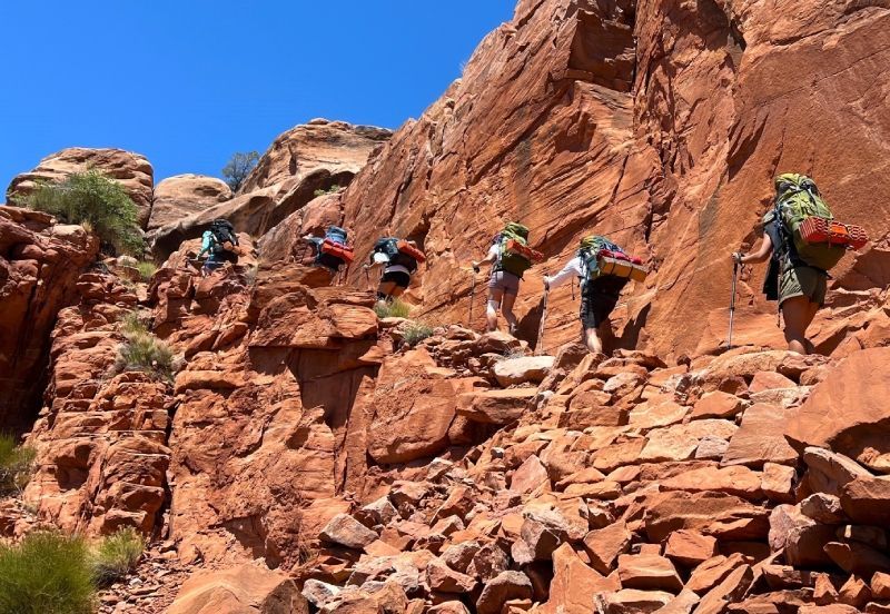 Women are hiking up a rocky hillside