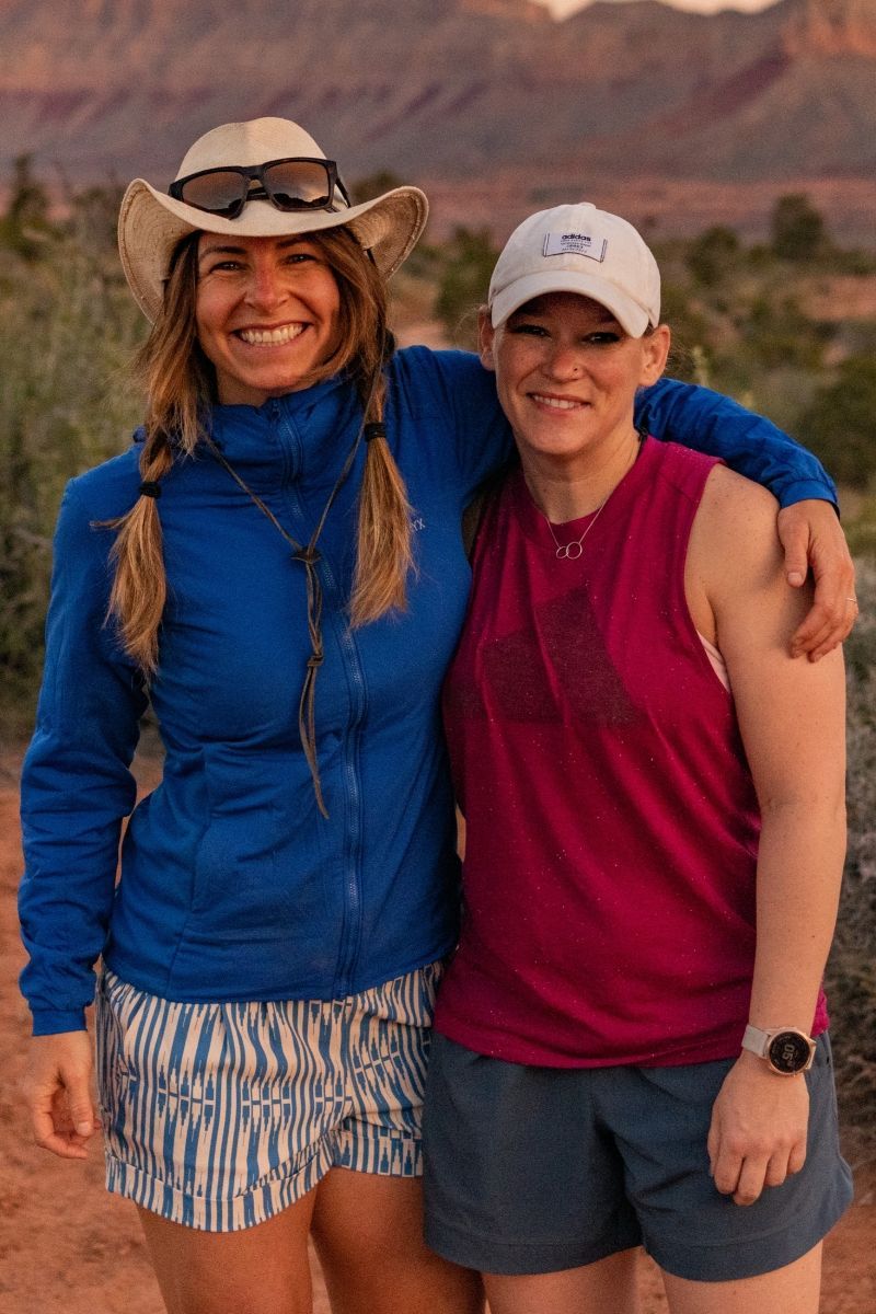 Two women are posing for a picture together in the desert.
