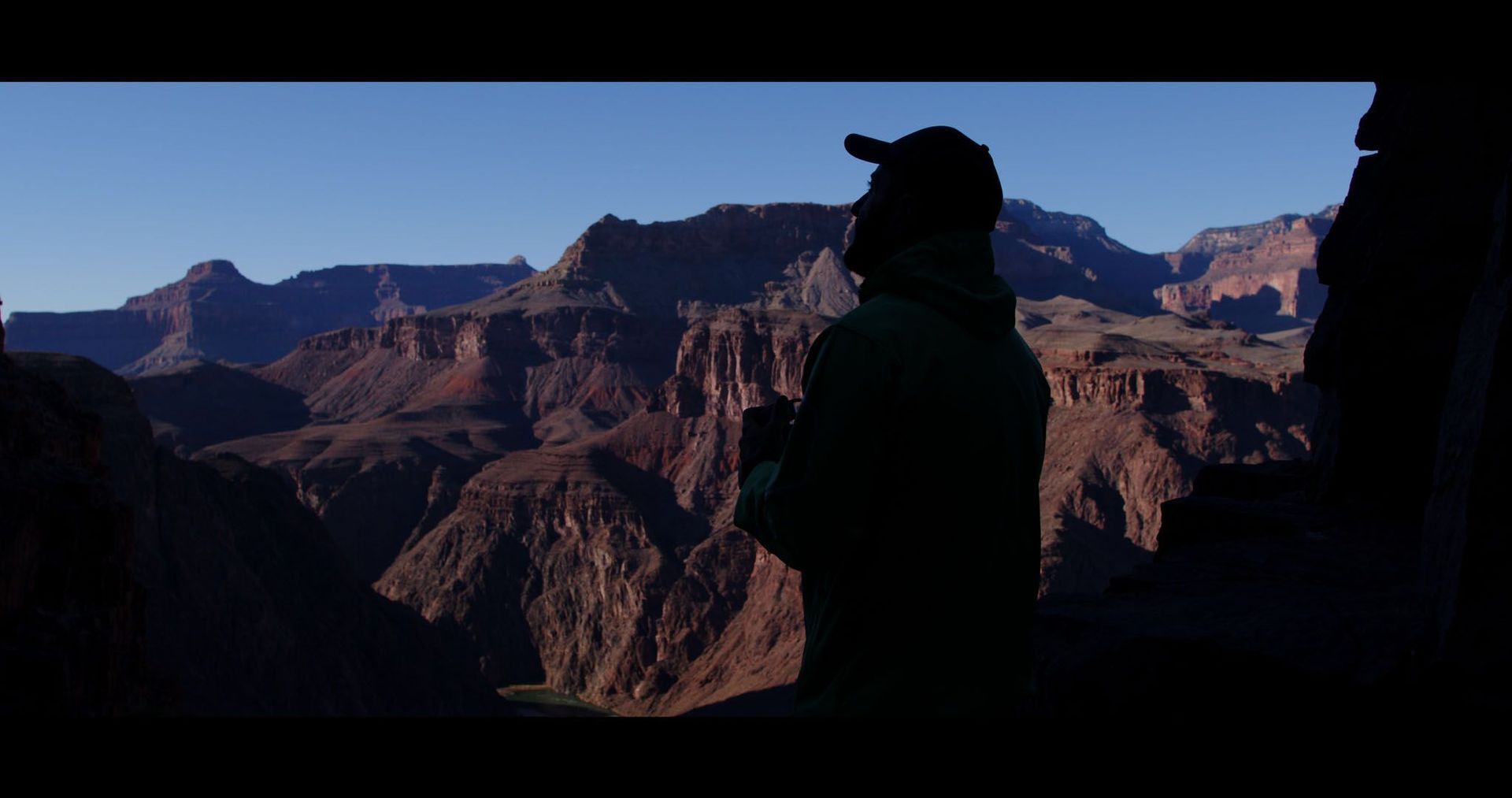 A silhouette of a person standing on top of a mountain.