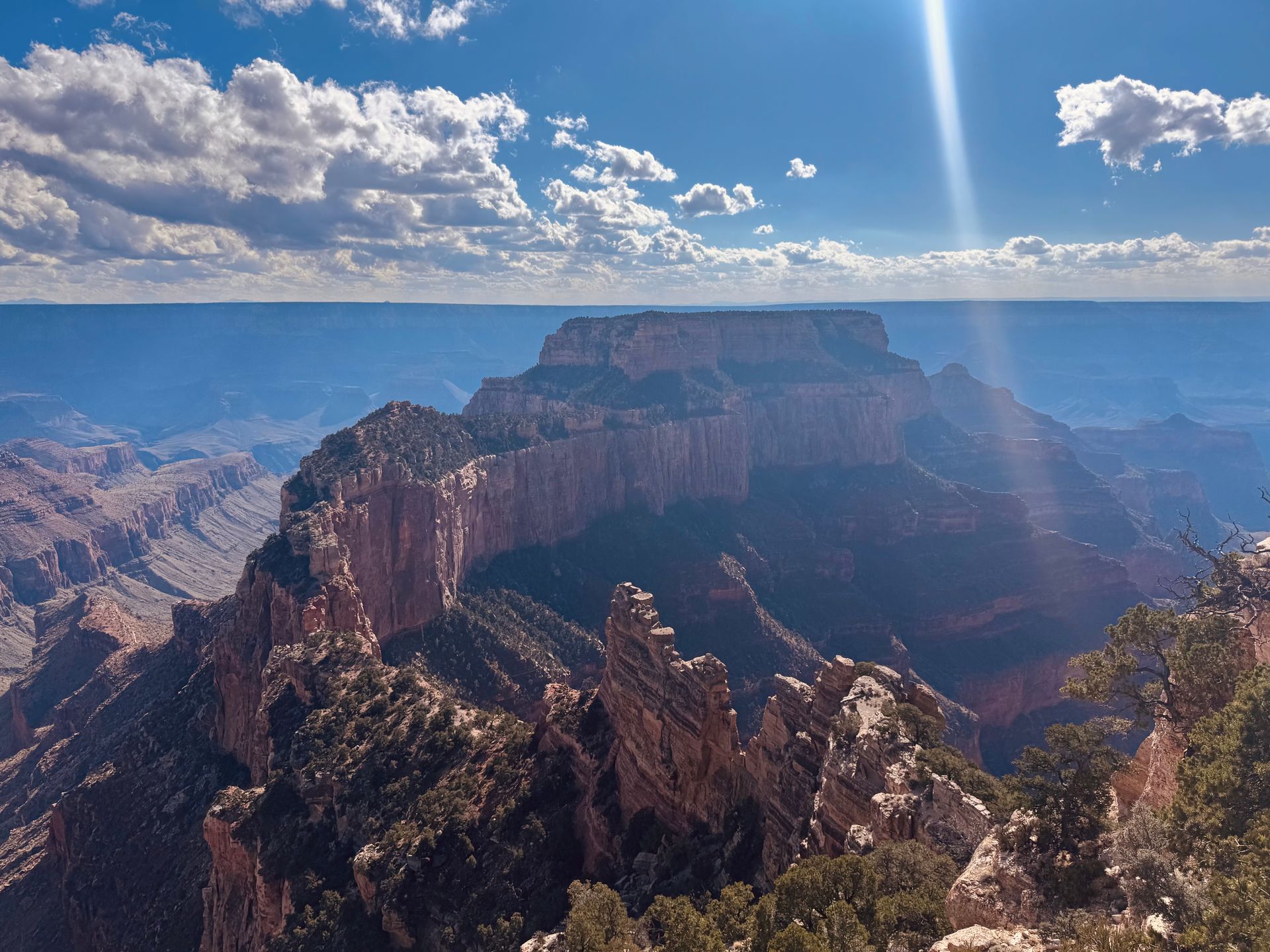 Canyon landscape with rocky formations, sunny sky, and clouds.