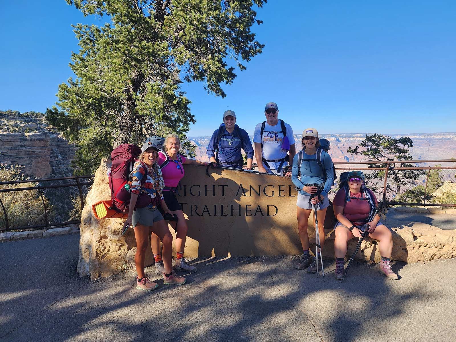 A group of people standing in front of a sign that says grand canyon trailhead