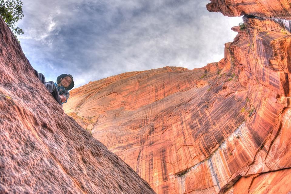 A person is climbing up a rock wall in the desert.