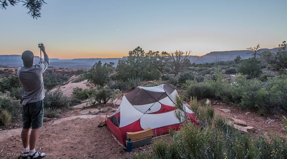 A man is taking a picture of a tent in the desert.