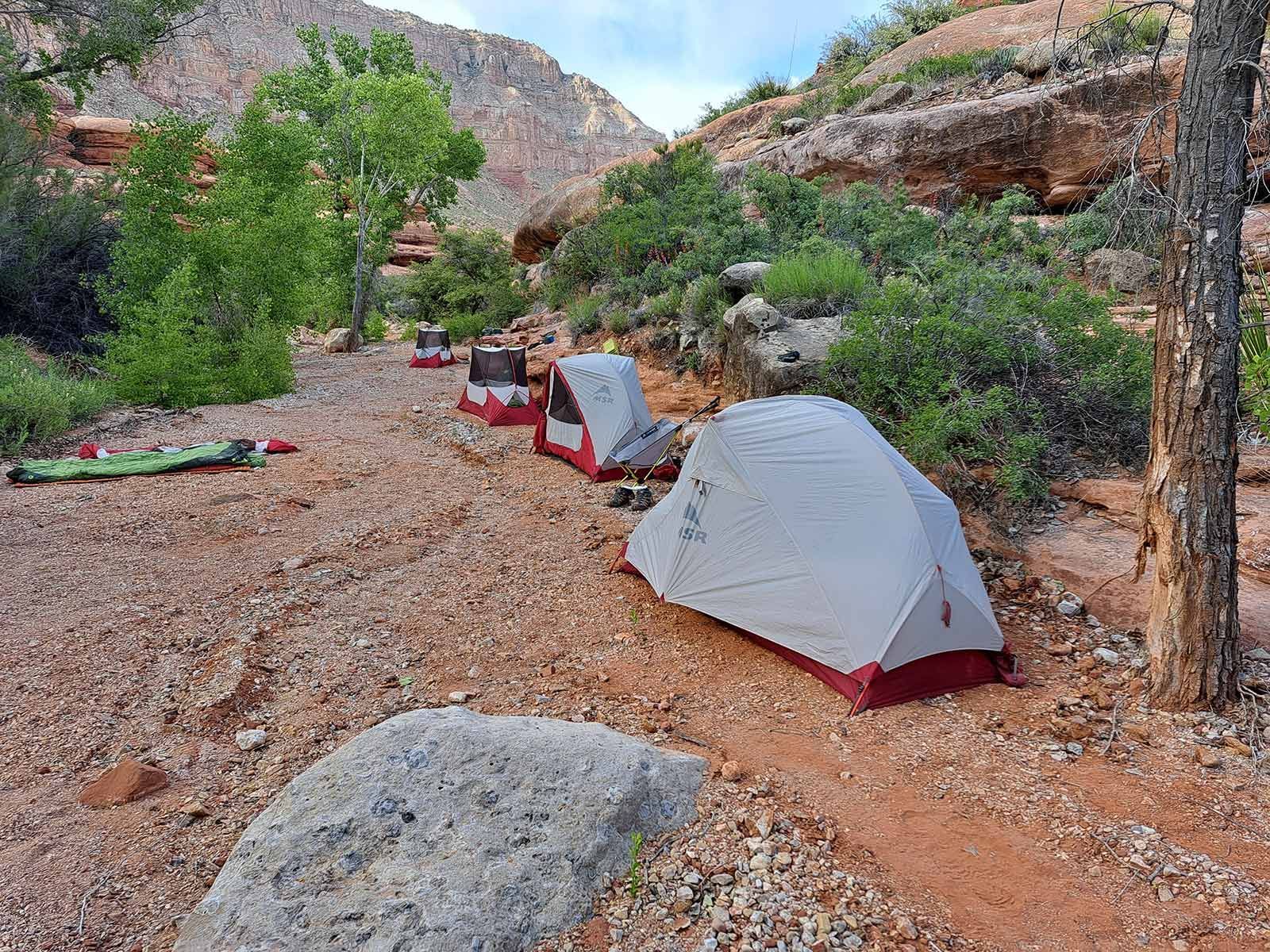 A row of tents are sitting on top of a rocky hillside.