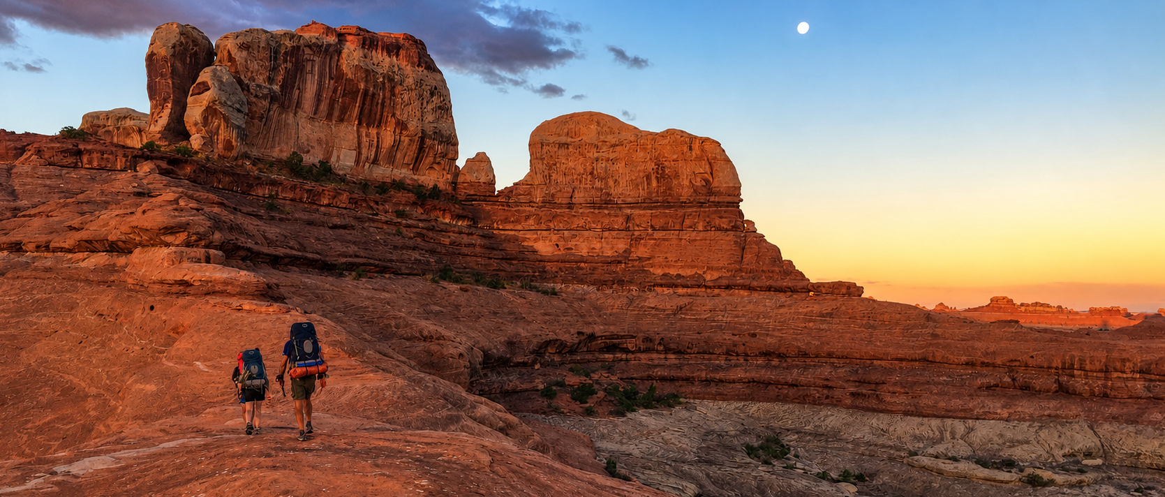 A couple of people standing on top of a rocky hill.