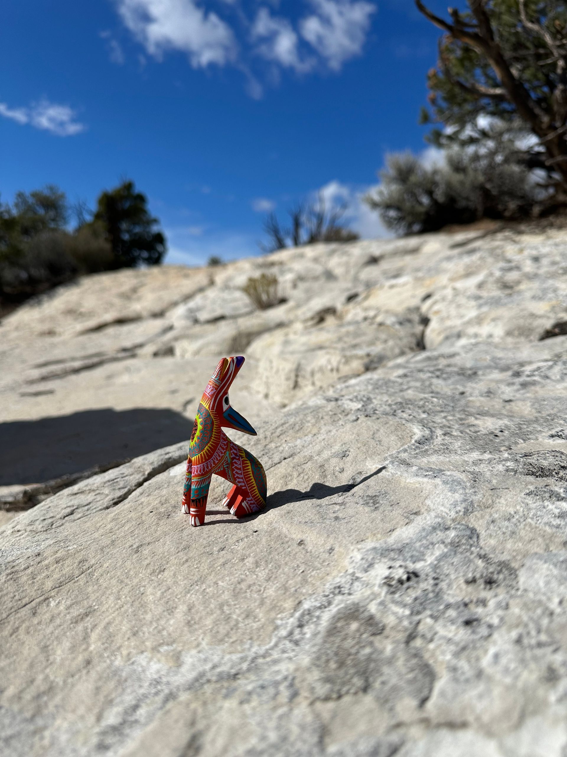 A small colorful figurine is sitting on top of a rock.