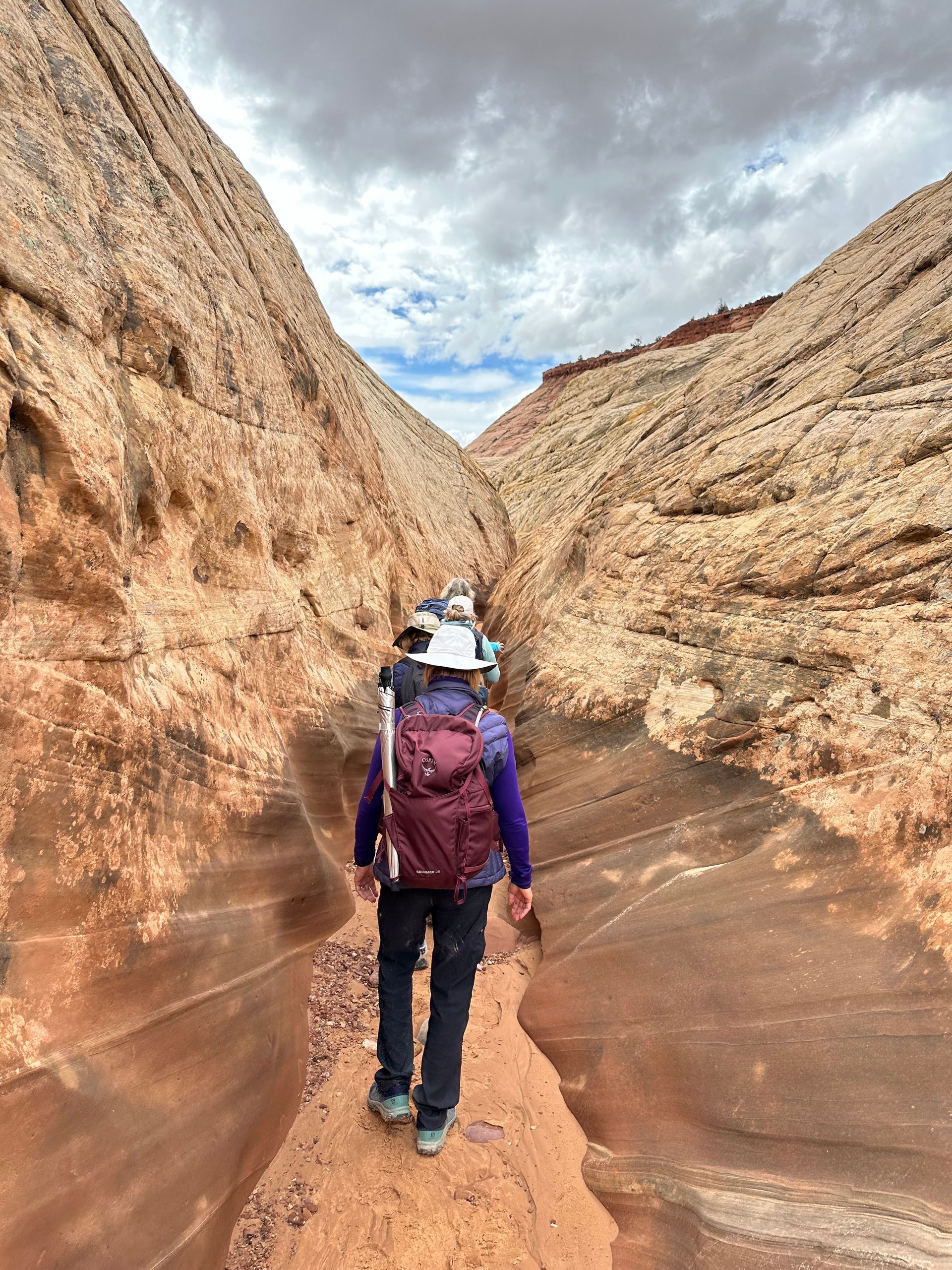 A woman with a backpack is walking through a canyon.