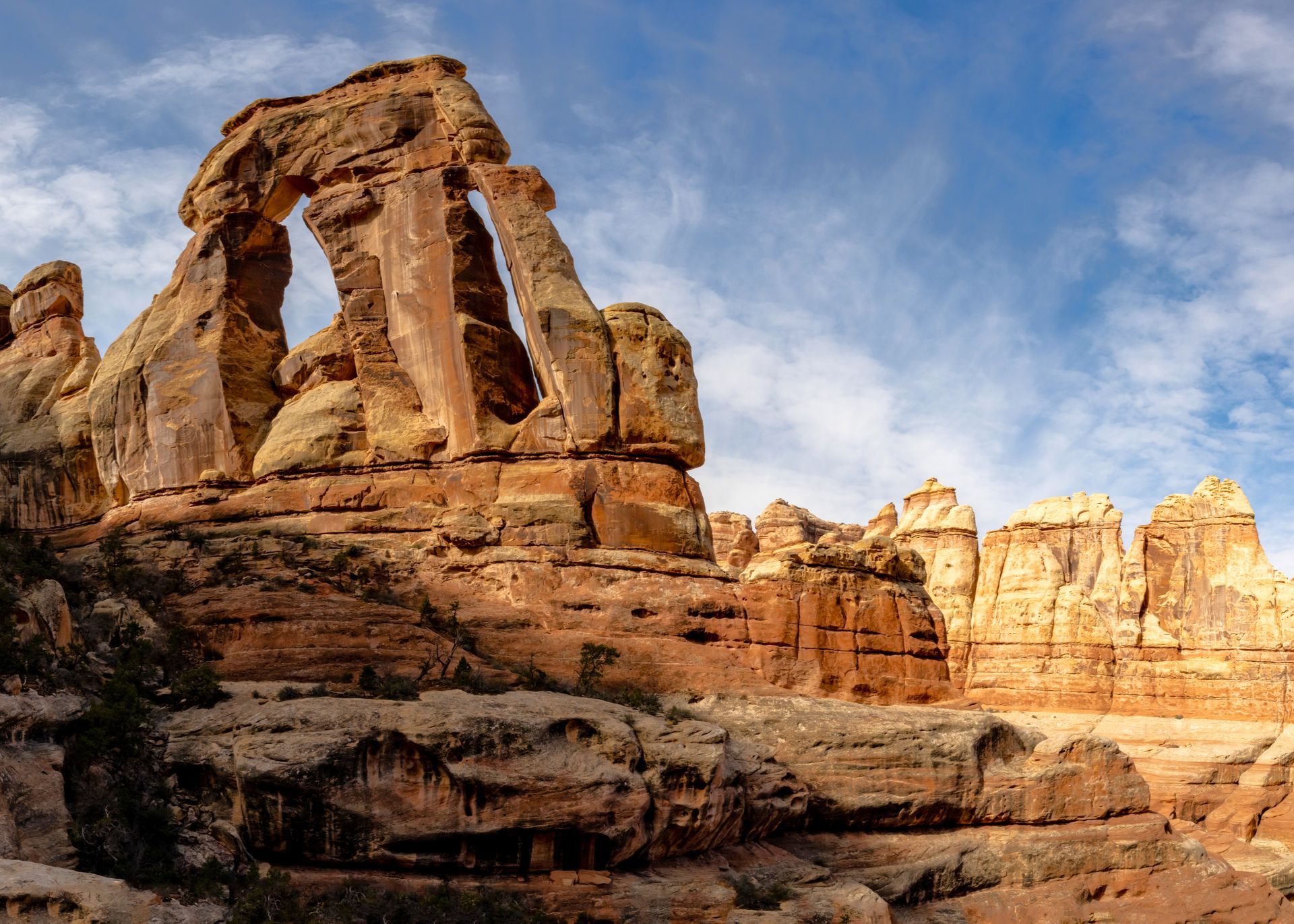 Red rock arch formation under a blue sky in a desert landscape.