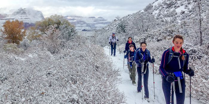 A group of people are walking in the snow on a trail.