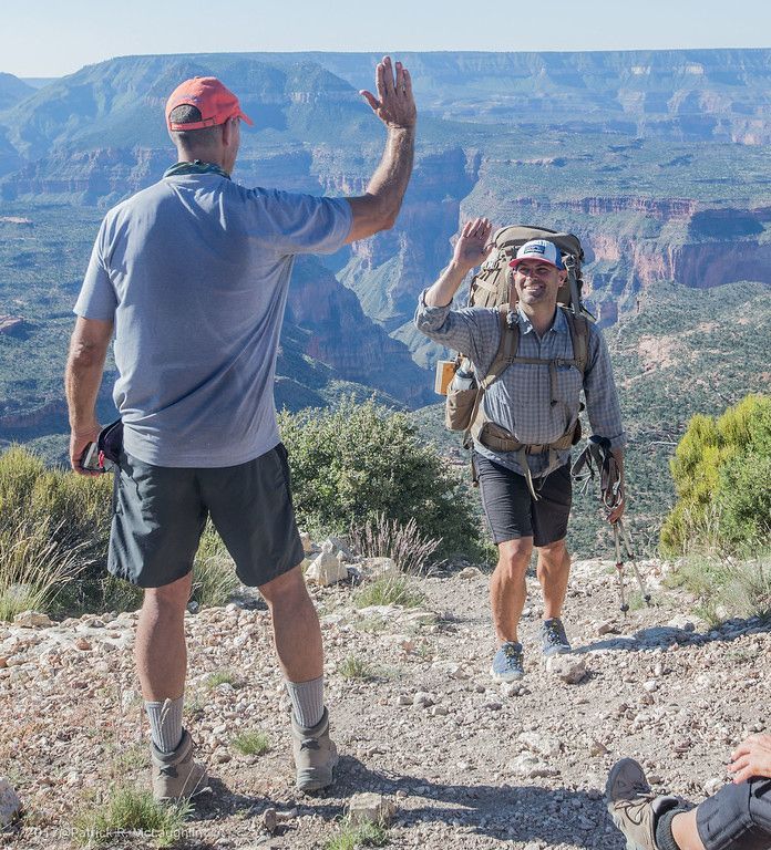 A man with a backpack is giving another man a high five