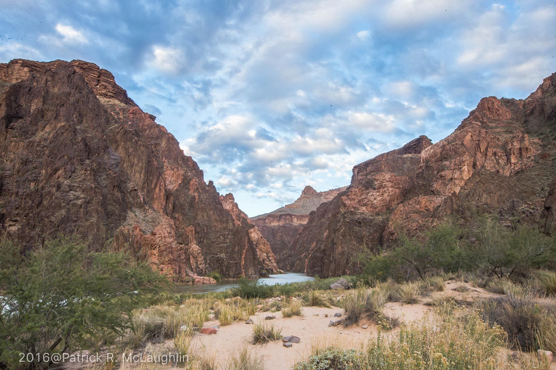 A man is standing on top of a mountain looking at the mountains.