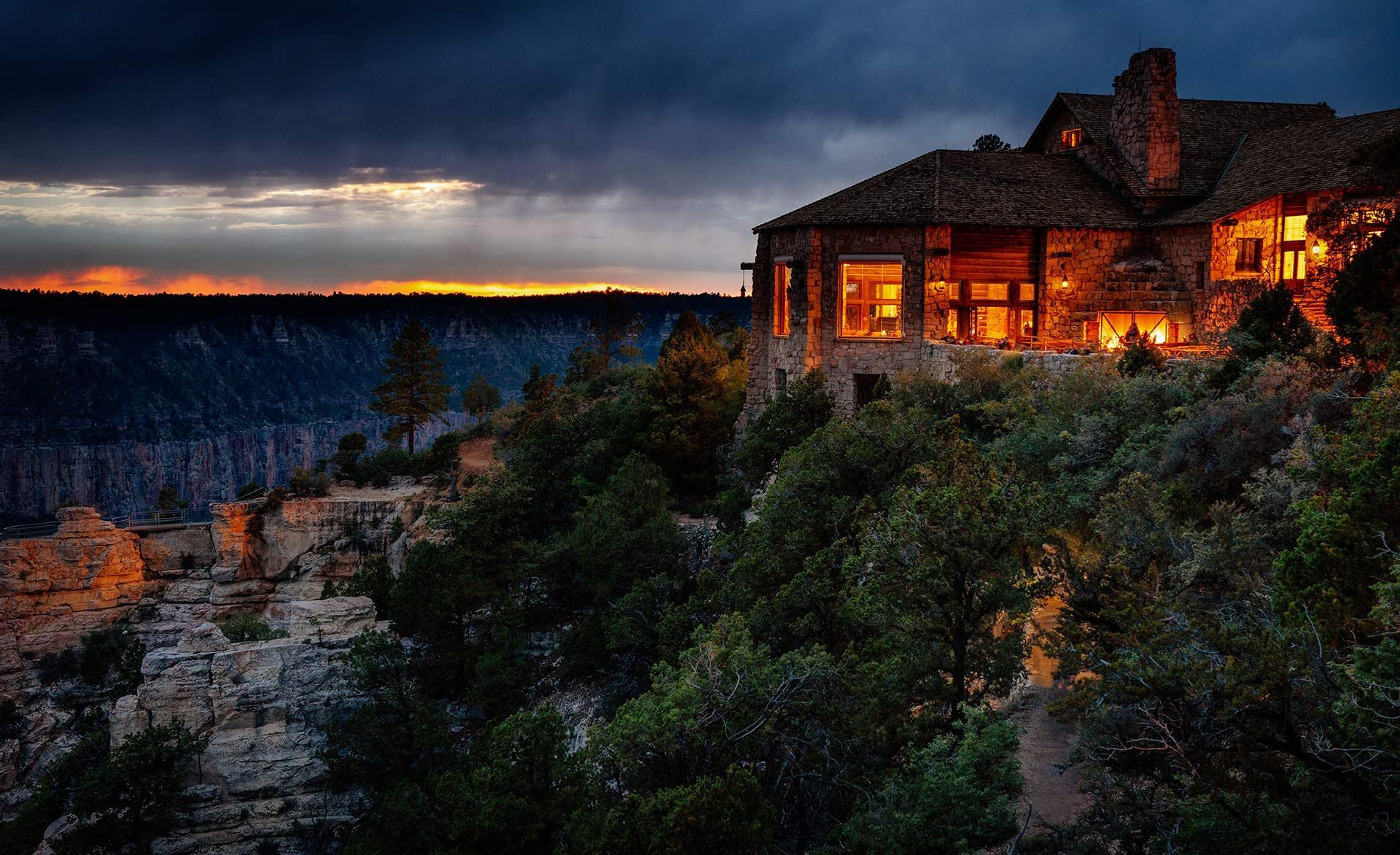 A large house is sitting on top of a cliff surrounded by trees.