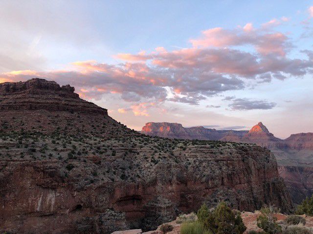 A sunset over a canyon with mountains in the background