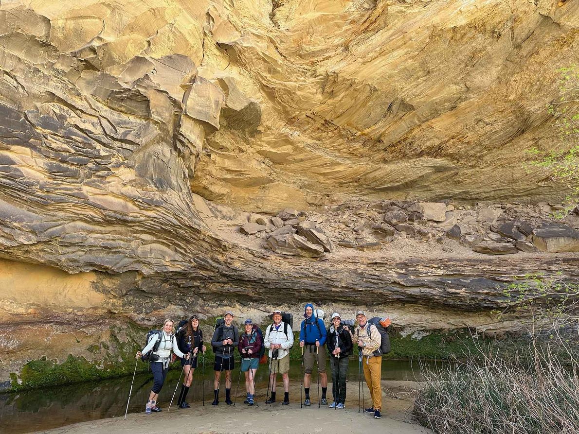 A Group of People Are Standing Under a Large Rock Formation