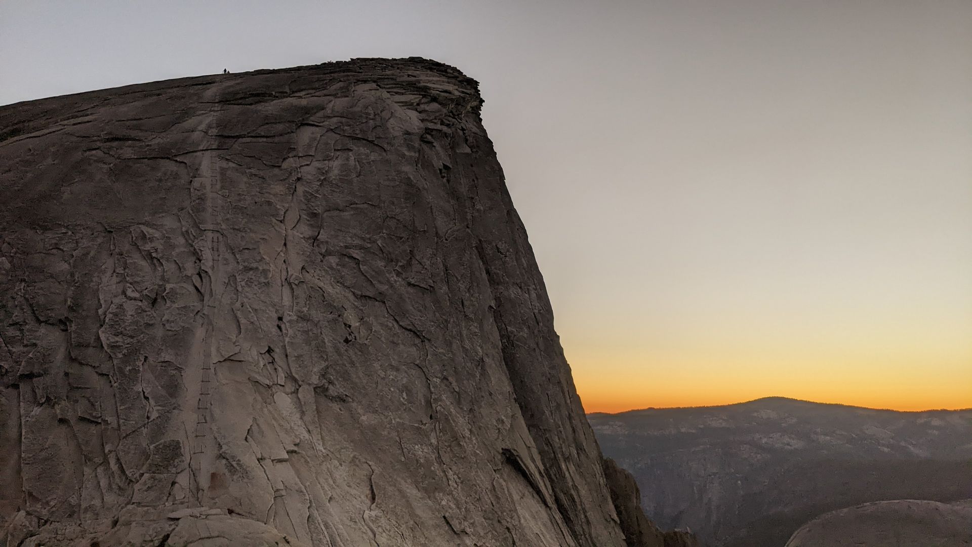 A large rocky cliff with a sunset in the background