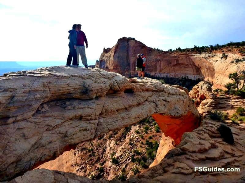 A couple standing on top of a rocky cliff with fsguides.com written on the bottom