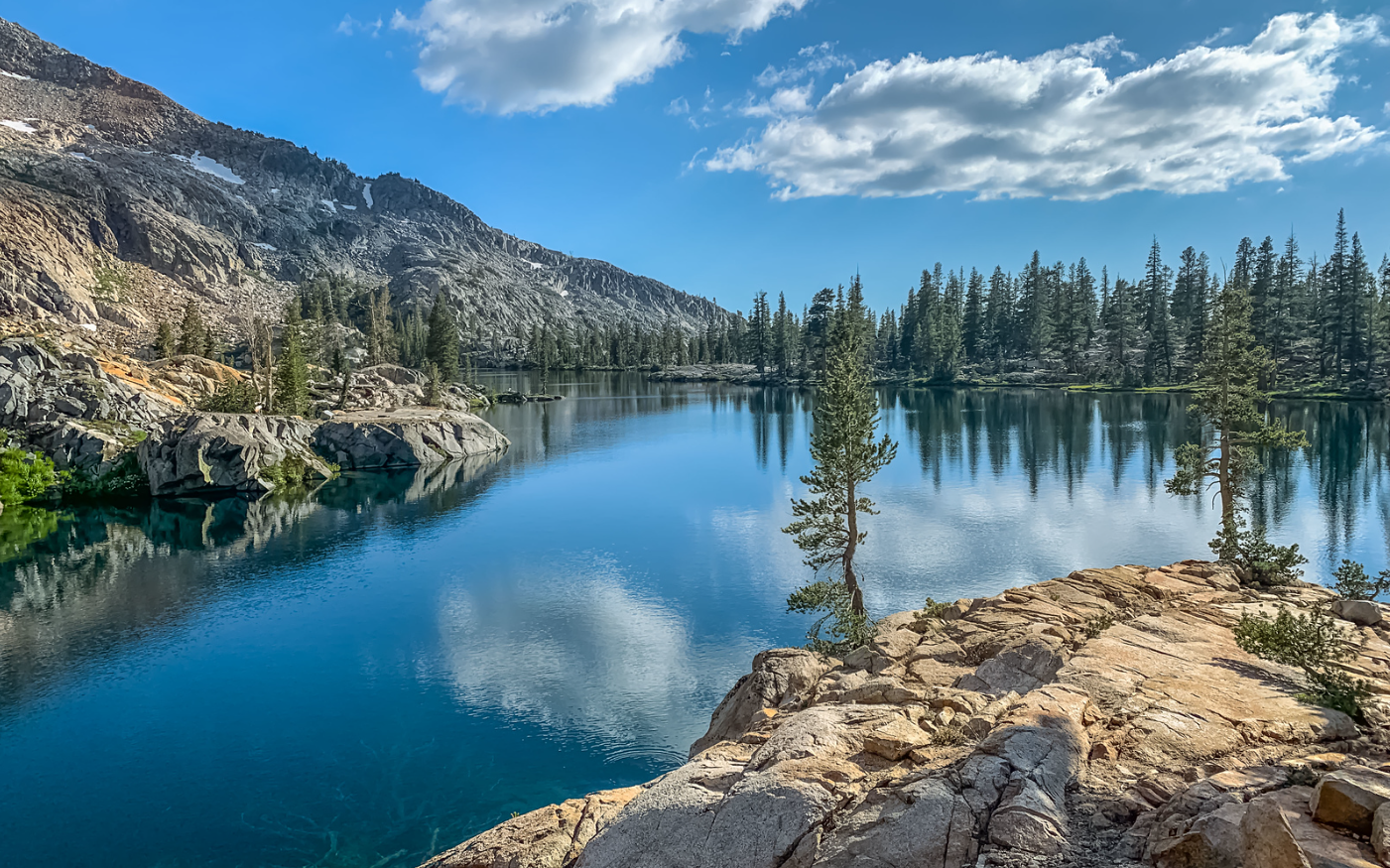 A person is swimming in a pool next to a waterfall.