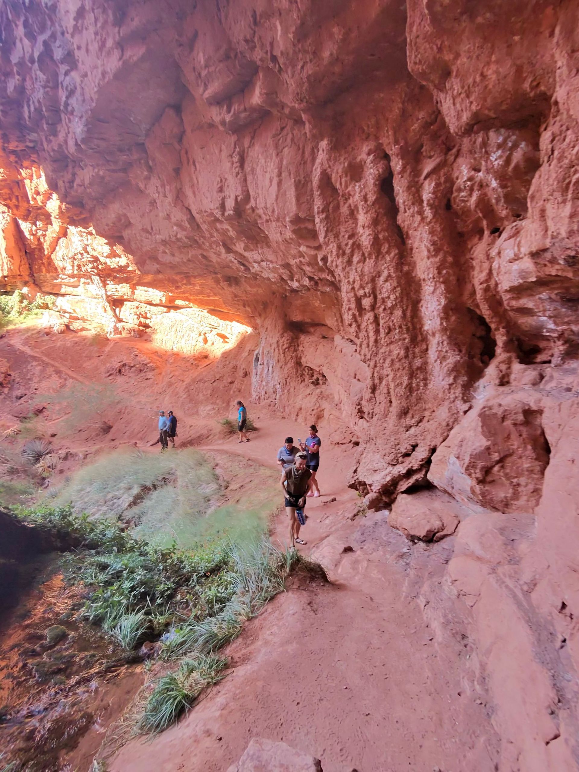 A group of people are standing on a rocky path in a cave.