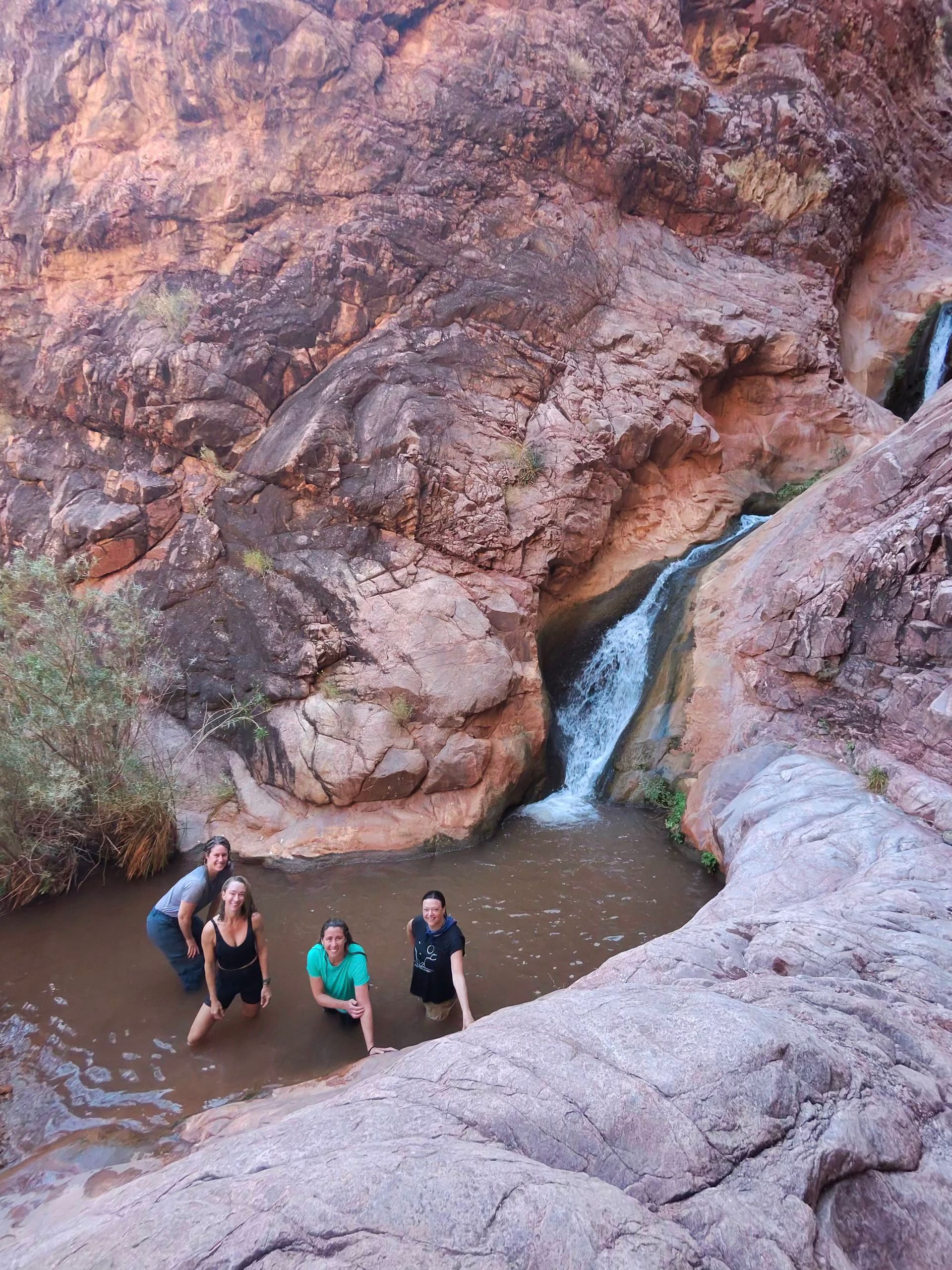 A group of people are standing in front of a waterfall.