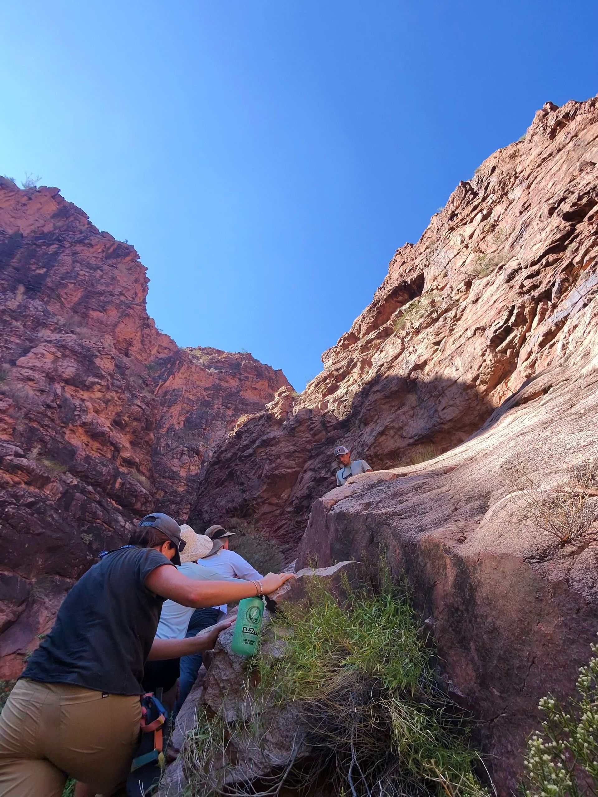 A group of people are climbing up a rocky cliff.