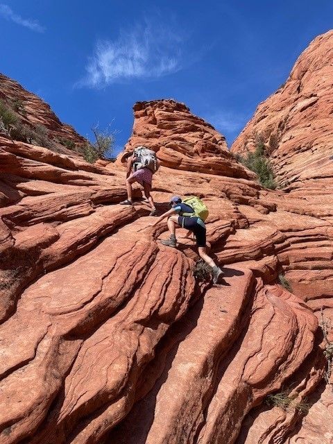 Two people are climbing up a rocky hillside