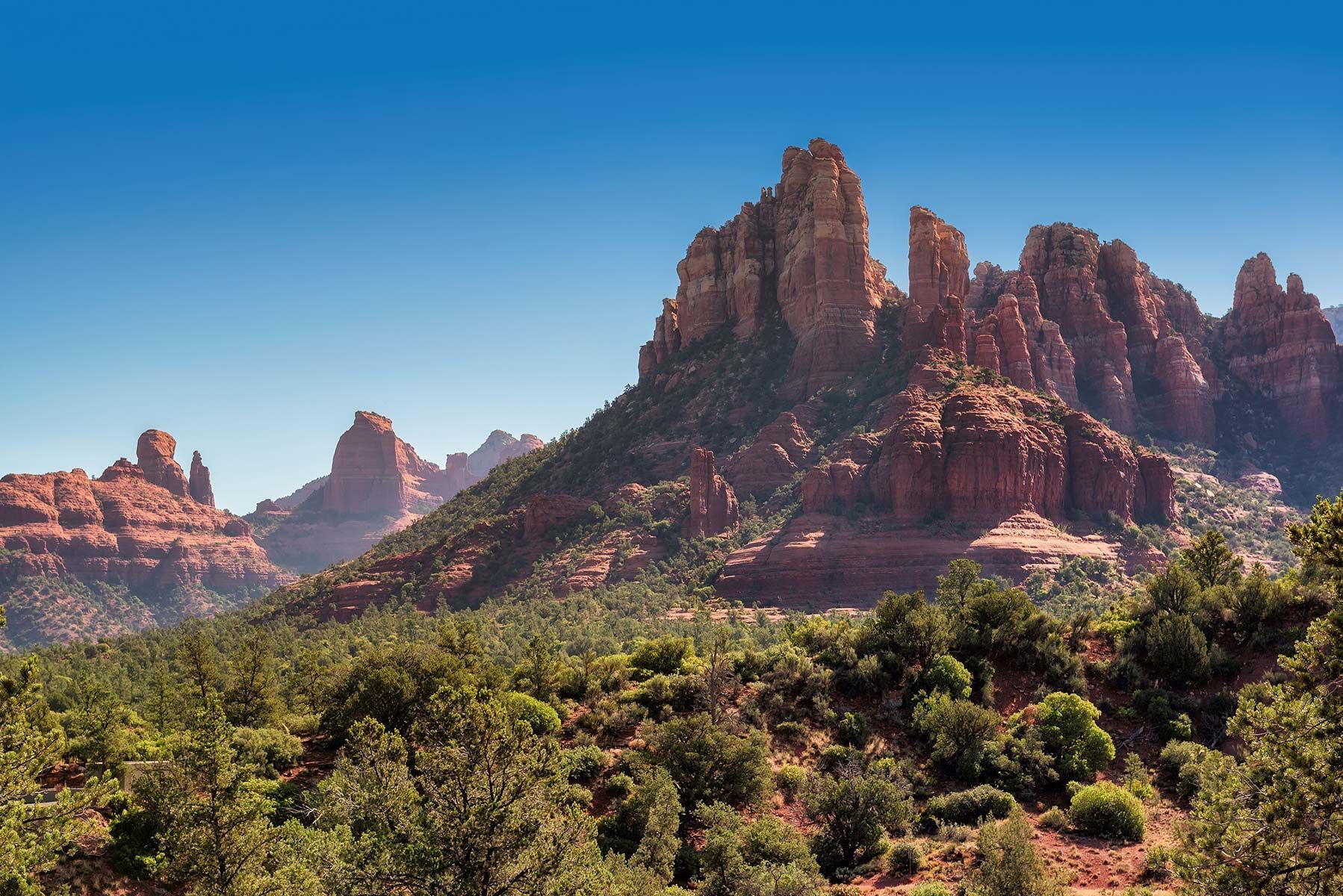 A mountain covered in trees and rocks with a blue sky in the background.