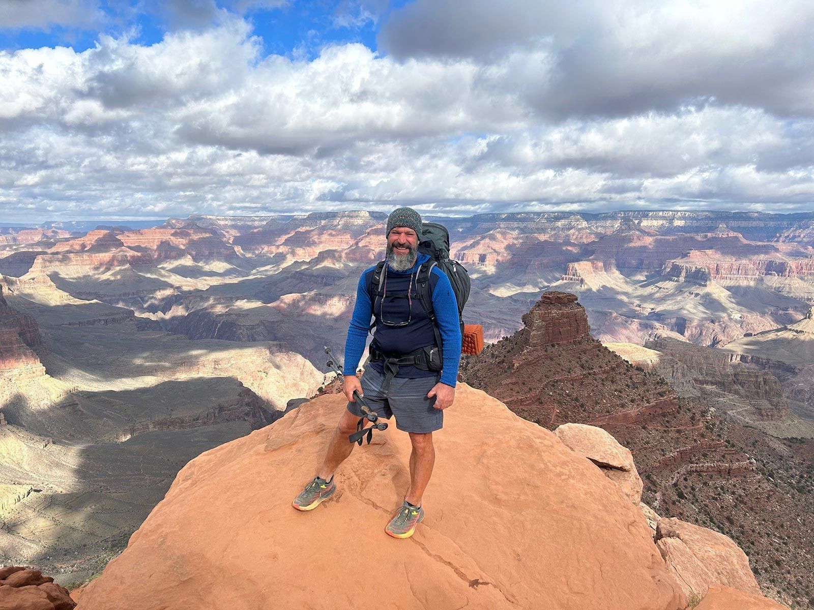 A man with a backpack is standing on top of a mountain.