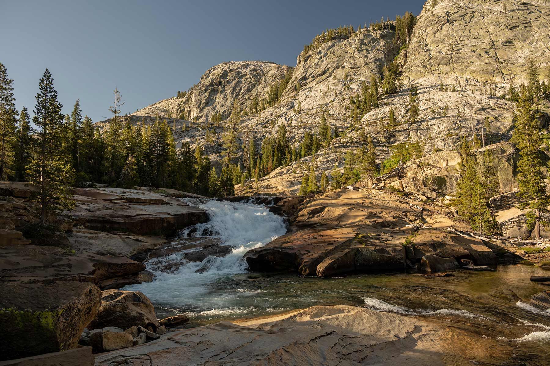 A waterfall in the middle of a mountain surrounded by trees