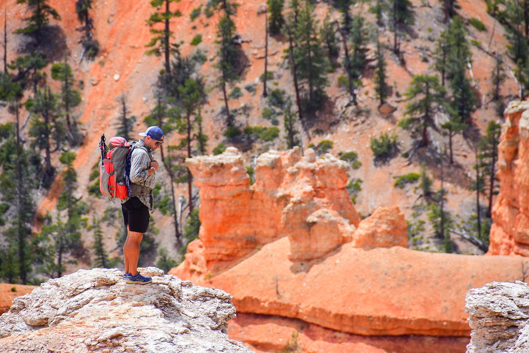 A man with a backpack is standing on top of a rocky hill.