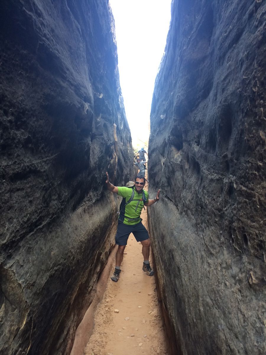 A man is standing in the middle of a narrow canyon.