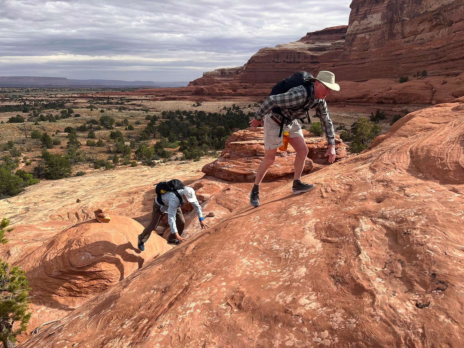 Two people are climbing up a rocky hillside.