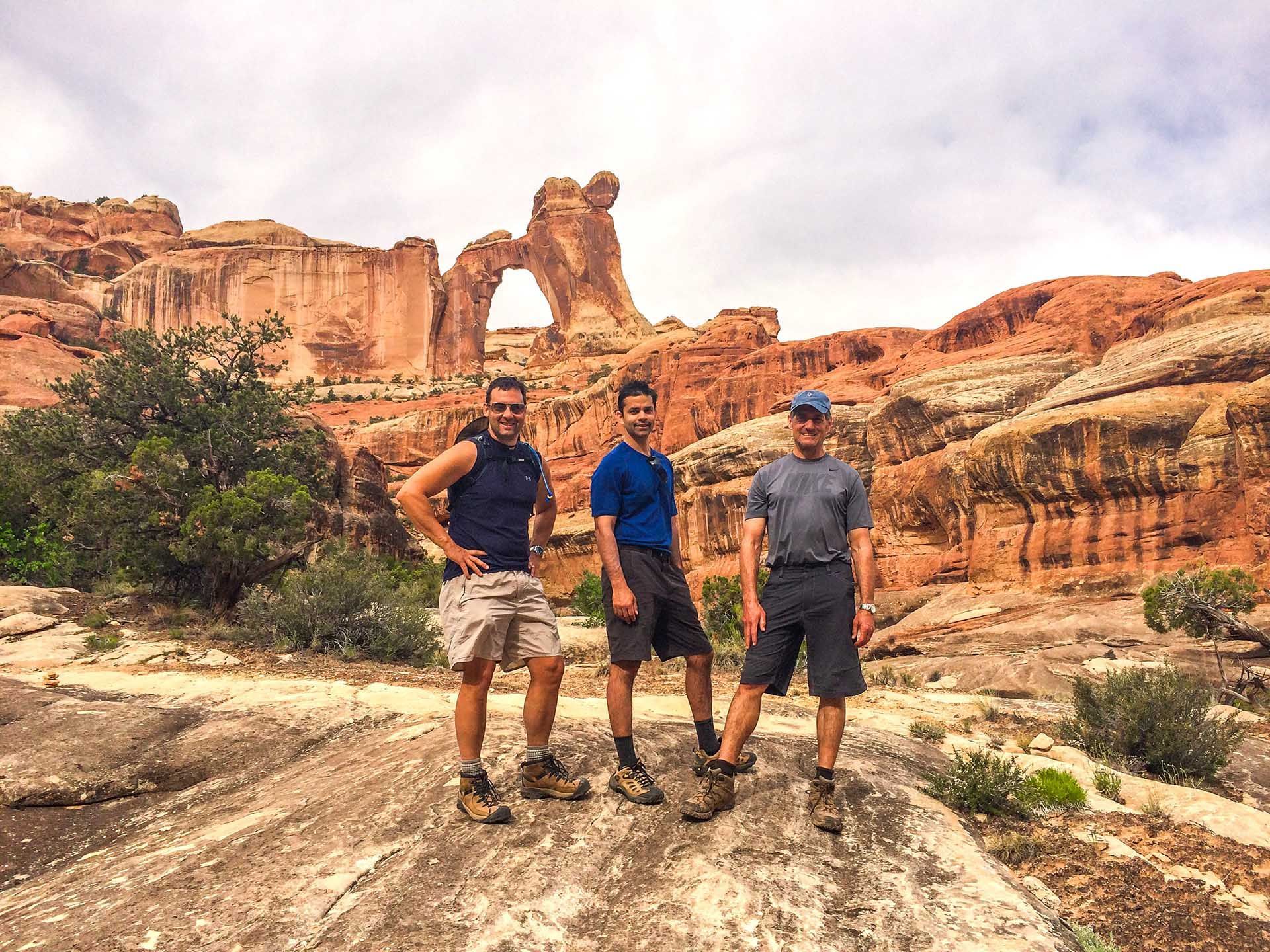 Three men are posing for a picture in front of a rock formation.