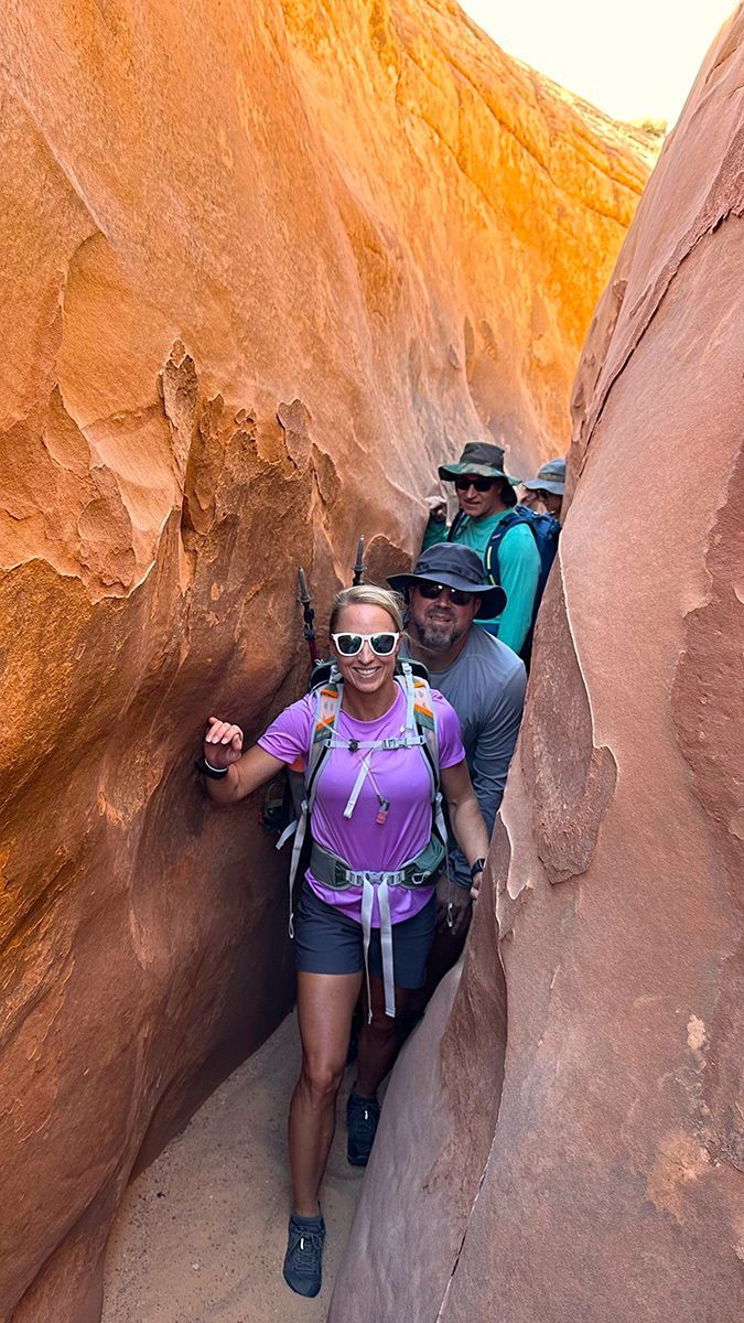 A group of people are hiking through a canyon.