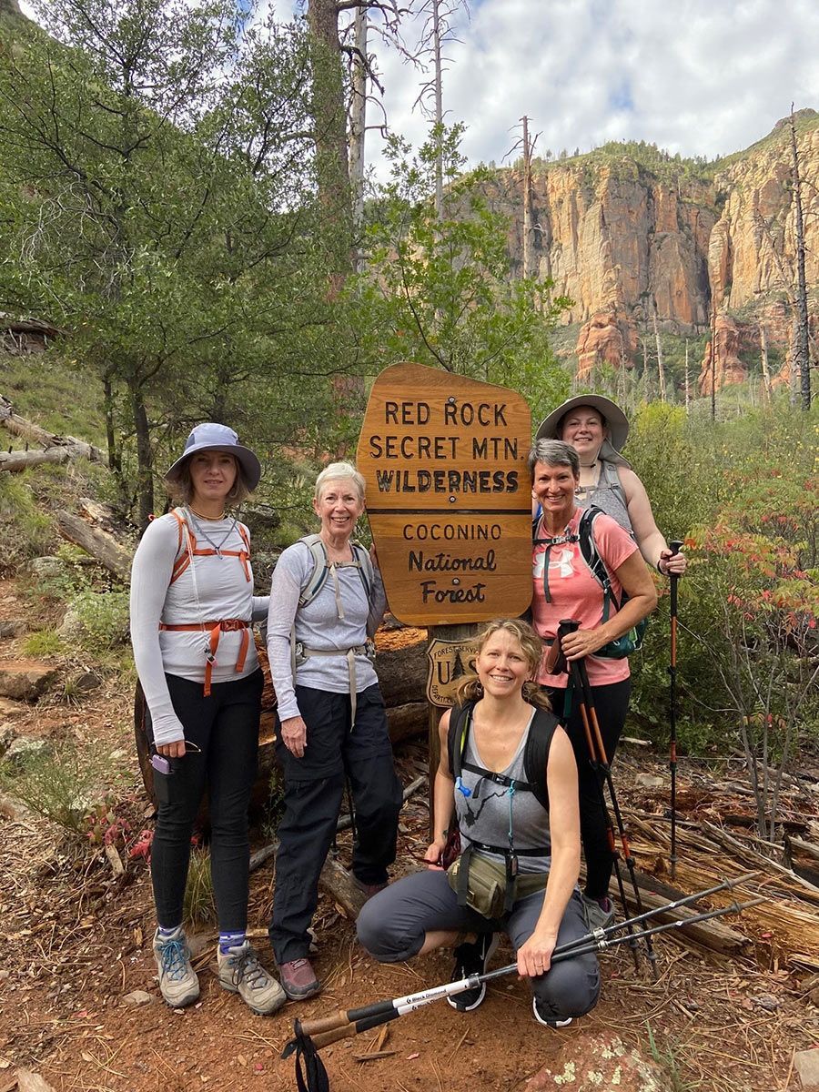 People pose next to a sign for a national forest, smiling