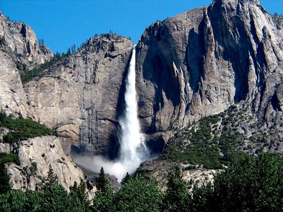 A waterfall in the middle of a mountain surrounded by trees