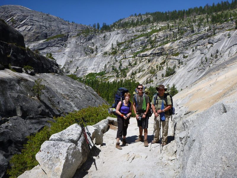 A group of people are standing on a trail in the mountains.