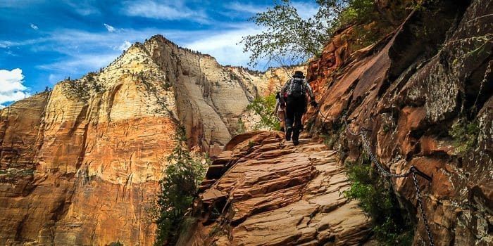 A person is walking down a rocky trail in the mountains.