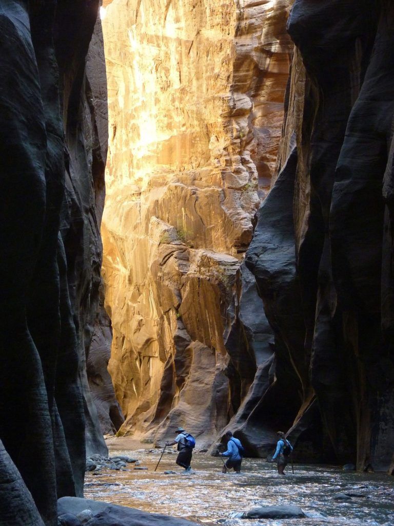 A couple of people are walking through a canyon.