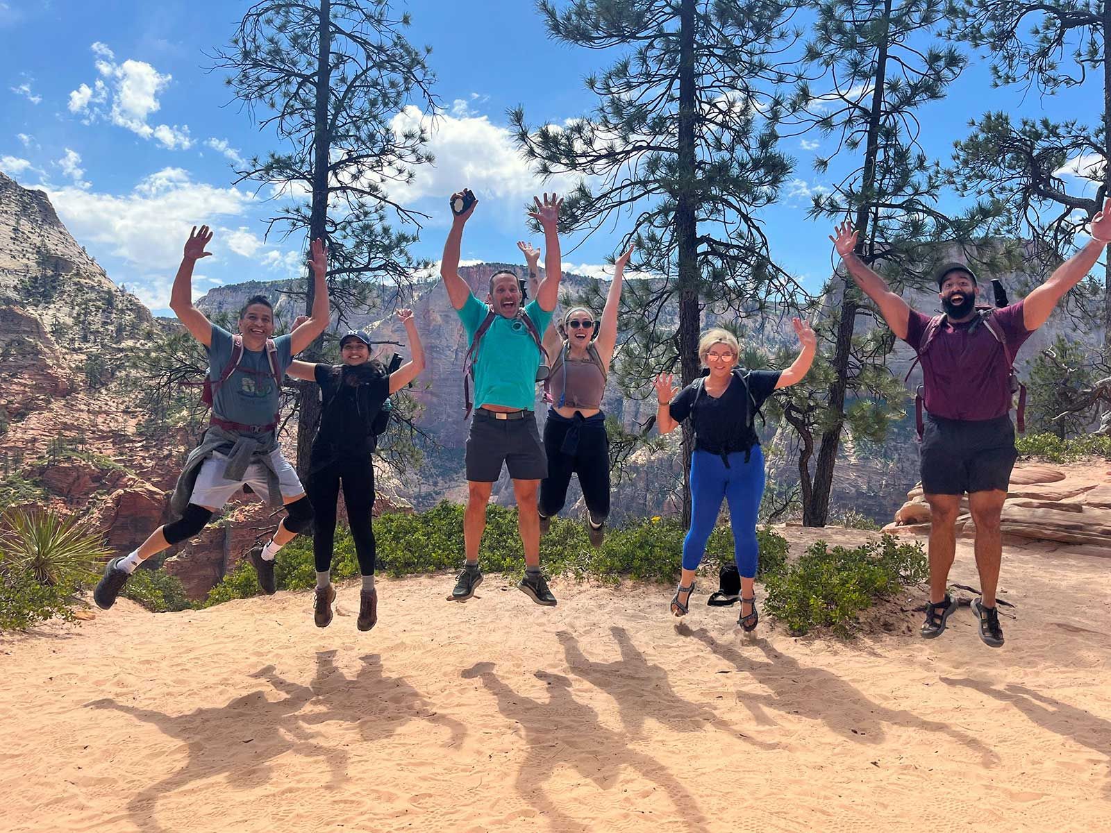 A group of people are jumping in the air in front of a mountain.