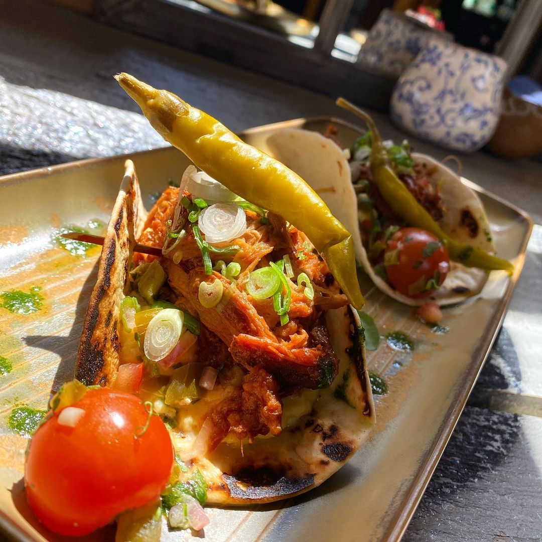 A close up of a plate of food with tomatoes and peppers on a table.