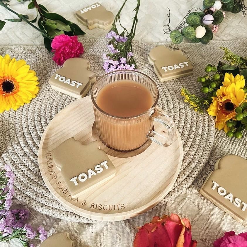 A cup of tea on a saucer with TOAST coasters around it