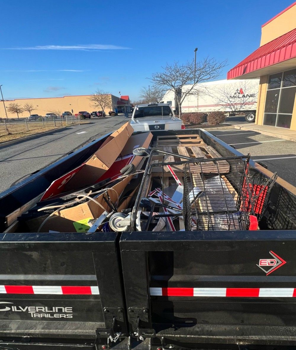 A dumpster filled with lots of junk is parked on the side of the road.