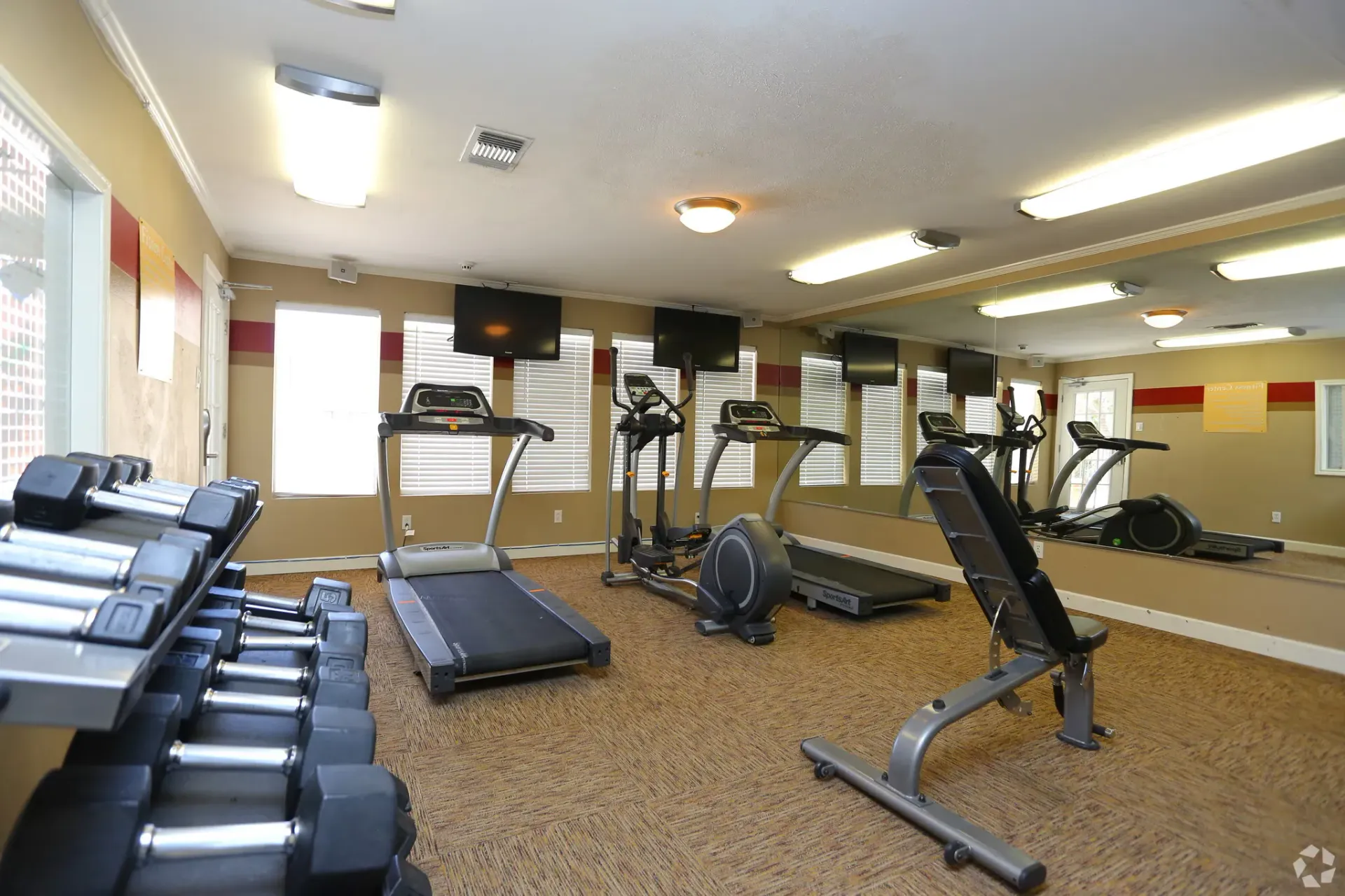 Gym with weights, treadmills, ellipticals, weight bench, mirrors, and TVs at Brookview, offering Odessa apartments for rent.