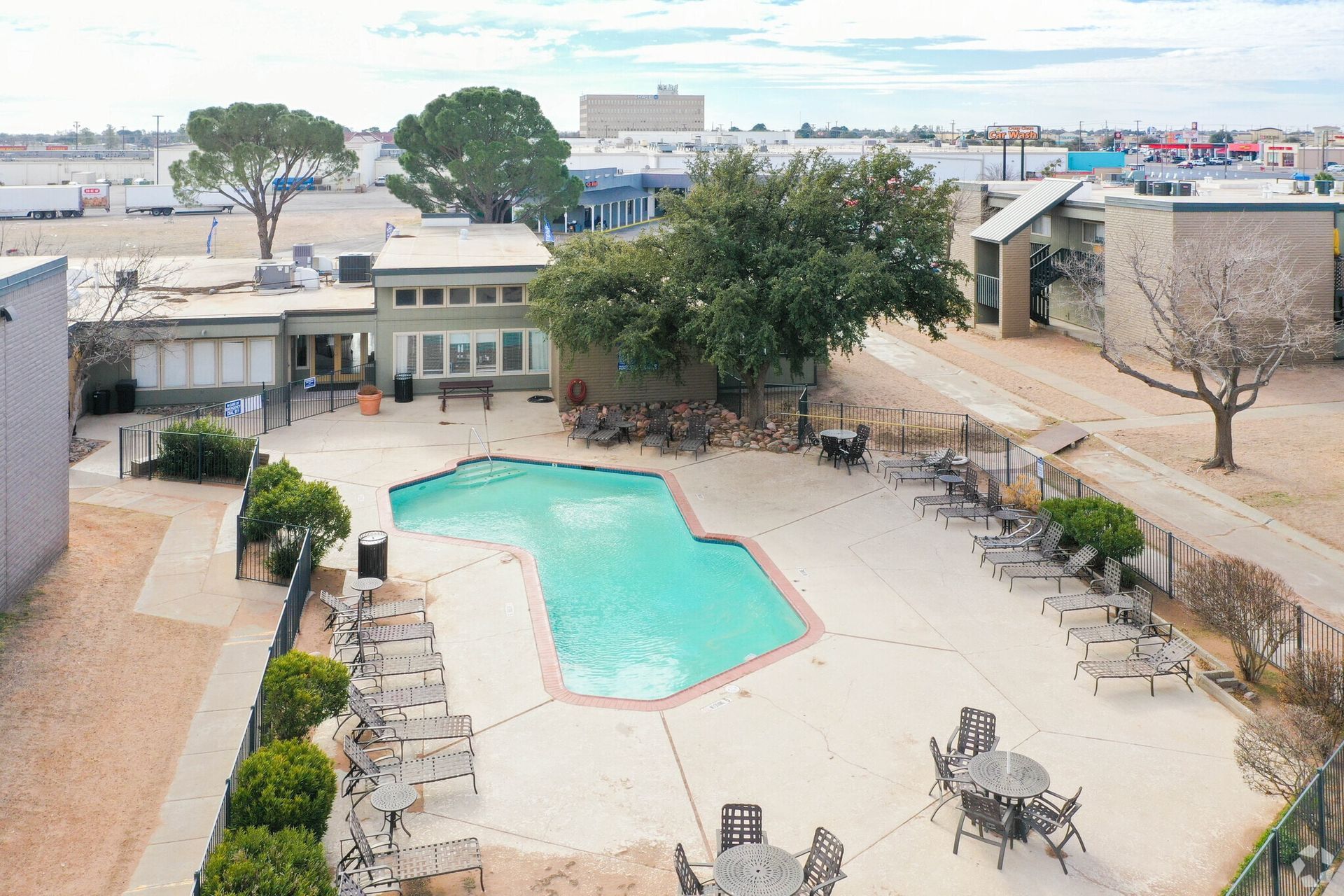 Aerial view of a swimming pool surrounded by lounge chairs and trees at Brookview, offering Odessa apartments for rent.