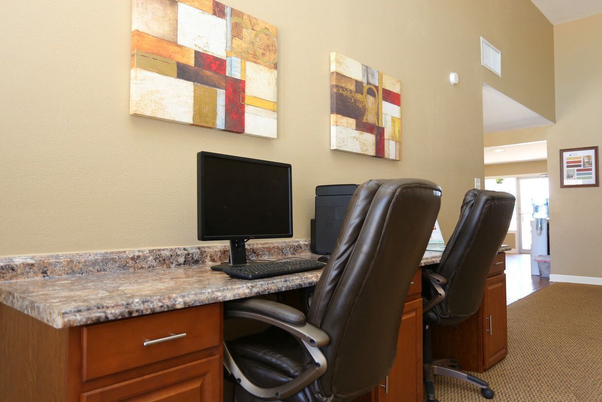Community computer desk area with two monitor setups and leather office chairs at Brookview, offering apartments for rent in Odessa, TX.