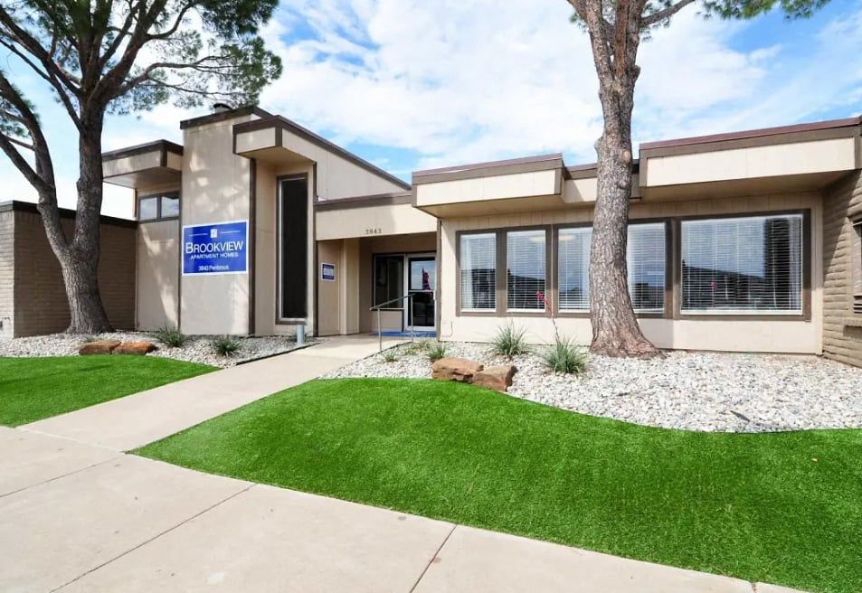 Exterior view of the Brookview leasing office with a sign, large windows, and manicured landscaping.