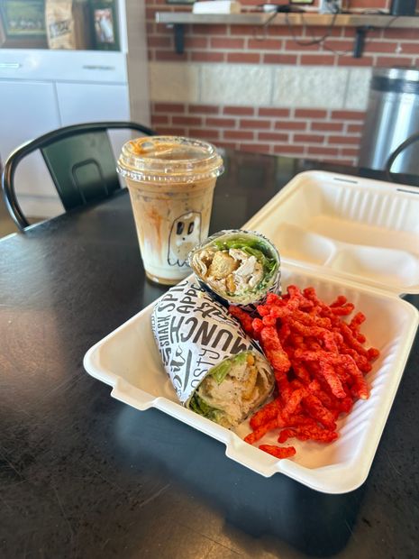 A sandwich and a drink are in a styrofoam container on a table.