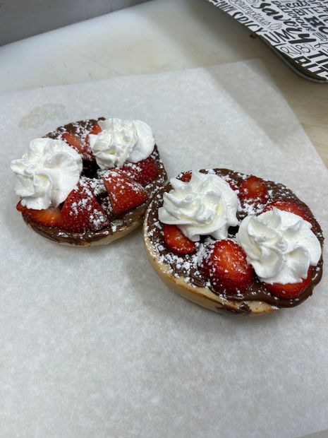 Two bagels with strawberries and whipped cream on them