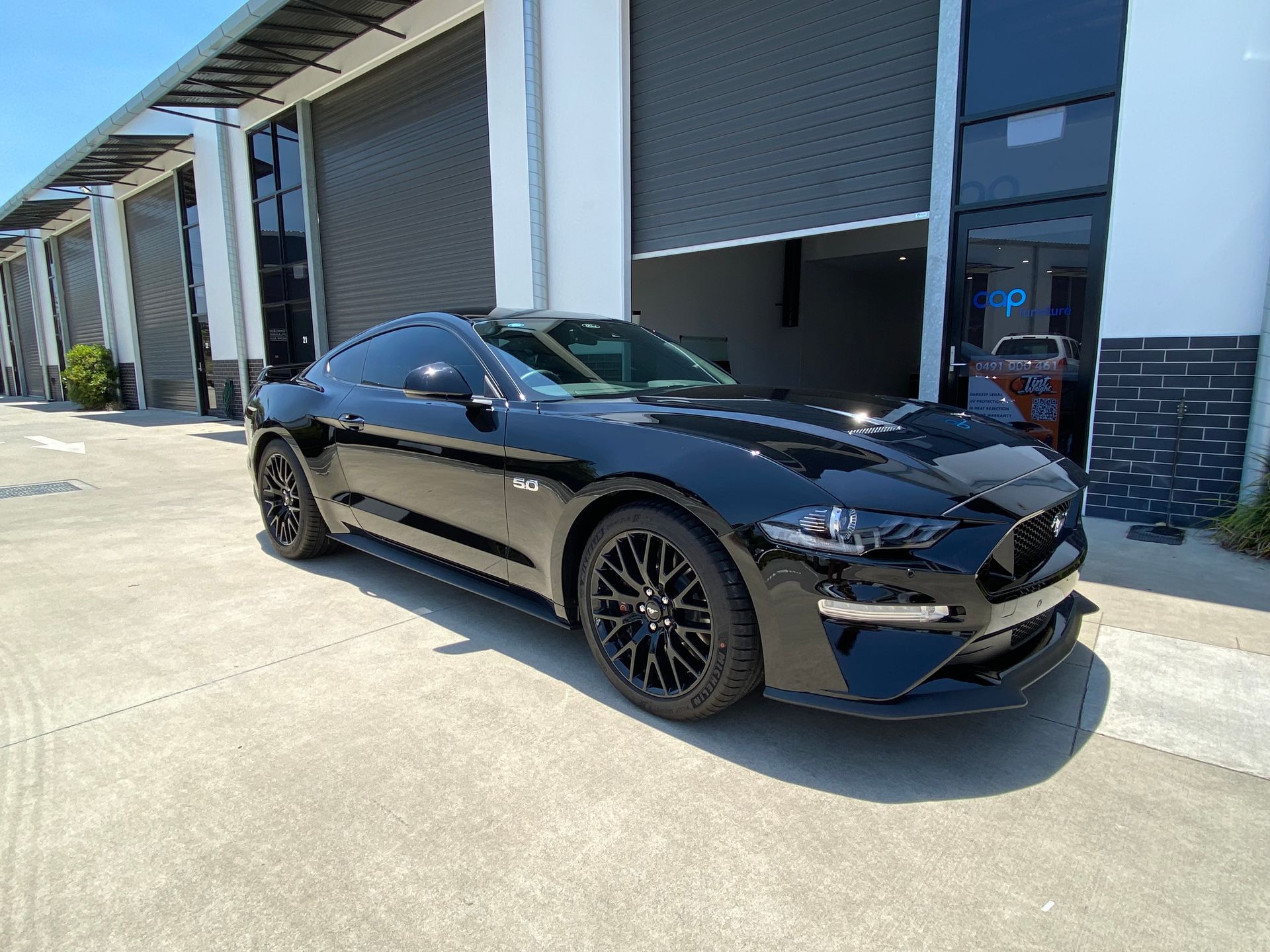 A black mustang is parked in front of a building.